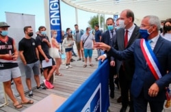 French Prime Minister Jean Castex, second right, and the mayor of Anglet, Claude Olive, right, look at people lining up to get vaccine shots in Anglet, southwestern France, July 17, 2021.