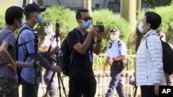 FILE - In this photo taken from video, Garry Pang Moon-yuen, center, is seen outside the West Kowloon Court, in Hong Kong, Nov. 29, 2021. 