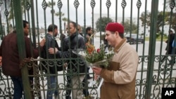 Seorang pria Tunisia hendak meletakkan bunga di pintu masuk Museum Nasional Bardo di Tunis (21/3). (AP/Michel Euler)