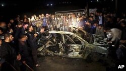 Palestinians surround the wreckage of a vehicle following an Israeli airstrike that killed three of Hamas militants near Deir Al Balah, central Gaza Strip, April 2, 2011