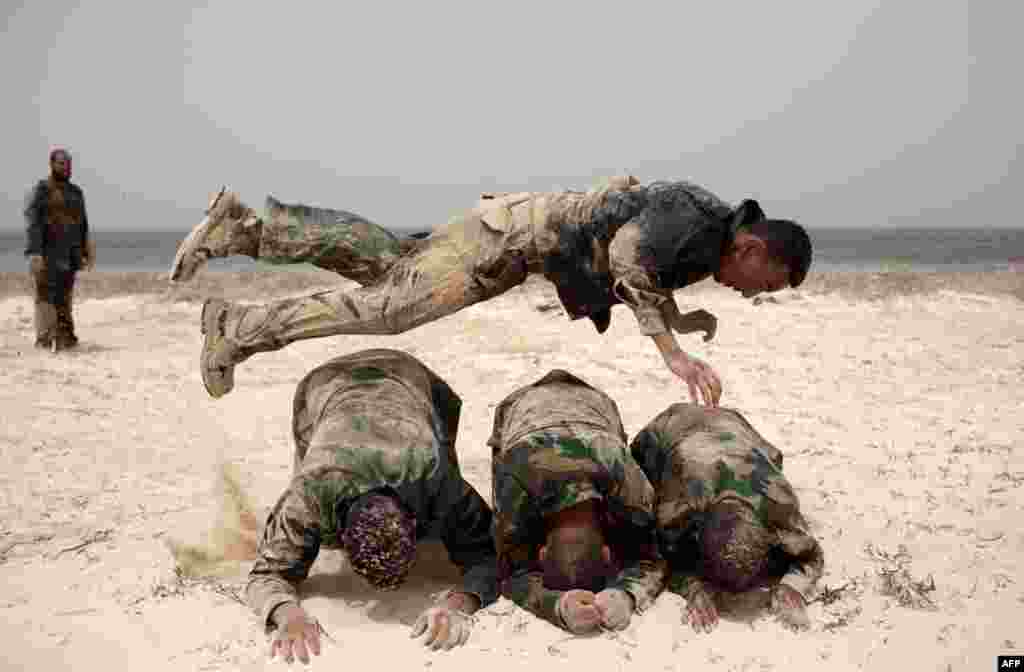 June 2: A Libyan volunteer jumps over his comrades during a military training course before going to the frontline in the rebelstrong hold of Benghazi, Libya. (AP Photo)