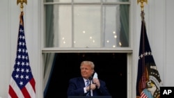 President Donald Trump removes his face mask to speak from the Blue Room Balcony of the White House to a crowd of supporters, Oct. 10, 2020, in Washington.