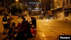 Demonstrators cover themselves with makeshift shields as police officers operate during an anti-government protest, following the ouster of Peru's former President Pedro Castillo, in Lima, Peru, Feb. 4, 2023. 