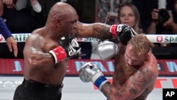 En esta instantánea Mike Tyson golpea a Jake Paul, durante su pelea de boxeo de peso pesado, el viernes 15 de noviembre de 2024, en Arlington, Texas. (Foto AP/Julio Cortez).