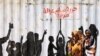 FILE - Civilians walk past graffiti reading in Arabic "Freedom, Peace, Justice and Civilian" in the Burri district of Khartoum, July 10, 2019. 