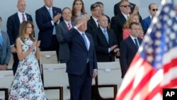 Presiden Perancis Emmanuel Macron (kanan), Presiden AS Donald Trump, dan Ibu Negara AS Melania Trump menyaksikan parade militer Hari Bastille di Champs Elysees, Paris, 14 Juli 2018.
