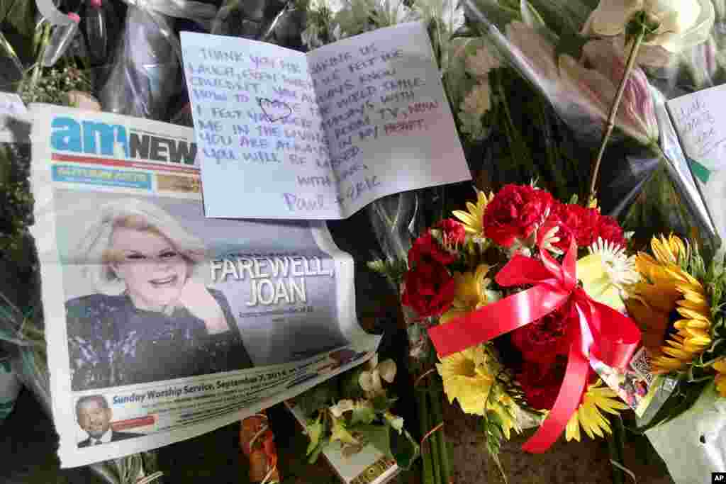 A newspaper, flowers and cards are part of a sidewalk memorial for comedian Joan Rivers at the doorstep of her apartment building in New York. Rivers, 81, died Thursday at a New York hospital following complications from surgery.