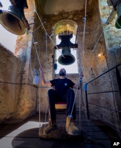 Joan Carles Osuna, a student of the Vall d'en Bas School of Bell Ringers, plays the bells at the 12th-century Sant Romà church, at the village of Joanetes, about two hours north of Barcelona, Spain, Saturday, June 29, 2024. (AP Photo/Emilio Morenatti)