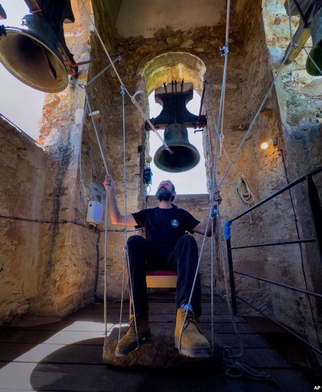 Joan Carles Osuna, a student of the Vall d'en Bas School of Bell Ringers, plays the bells at the 12th-century Sant Romà church, at the village of Joanetes, about two hours north of Barcelona, Spain, Saturday, June 29, 2024. (AP Photo/Emilio Morenatti)