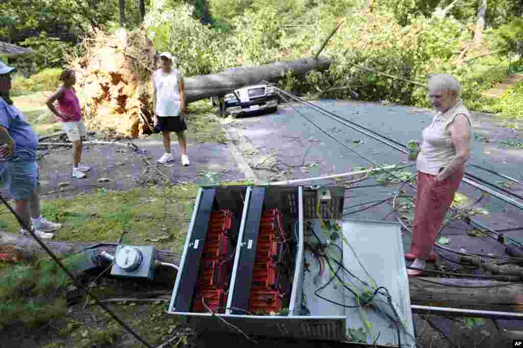 Marilyn Golias, right, looks at the remains of a utility pole which fell across the street from her house in Falls Church, Va., June 30, 2012.