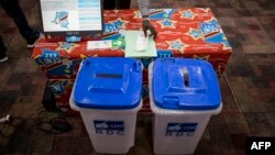 Une nouvelle machine à voter devant être utilisée lors des élections en République démocratique du Congo (RDC) est installée sur une table à côté de deux urnes le 21 février 2018 à Kinshasa.