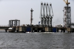 FILE - People ride a boat past an oil discharge facility in Lagos, Nigeria, Nov. 10, 2016.