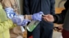 In this March 27, 2020 photo, a patient arriving to pick up medication for opioid addiction is given hand sanitizer at a clinic in Olympia, Wash., that is currently meeting patients outdoors and offering longer prescriptions in hopes of reducing the…