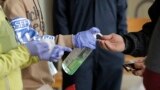 In this March 27, 2020 photo, a patient arriving to pick up medication for opioid addiction is given hand sanitizer at a clinic in Olympia, Wash., that is currently meeting patients outdoors and offering longer prescriptions in hopes of reducing the…