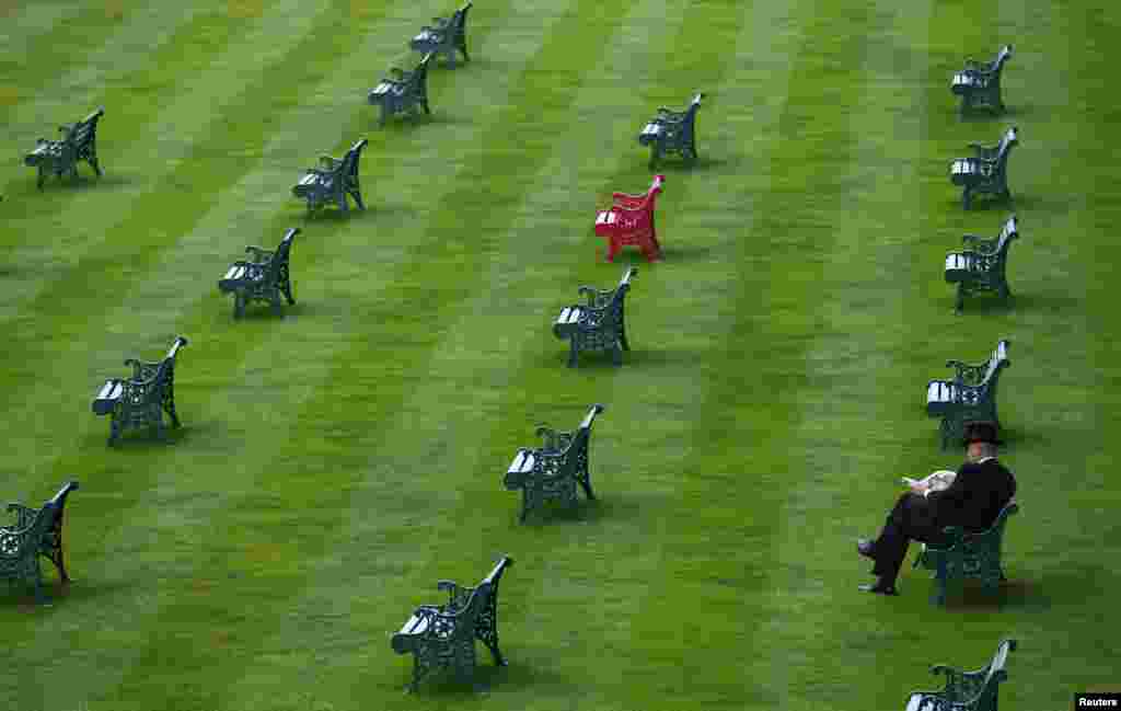 Seorang pria membaca koran di Lapangan Royal Enclosure pada hari pertama menjelang festival balap kuda di kota Ascot, Inggris selatan.