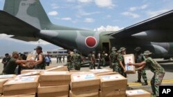 Personel militer Indonesia dan Jepang membongkar bantuan untuk korban bencana gempa bumi dan tsunami dari pesawat kargo Angkatan Udara Jepang di bandara Mutiara Sis Al-Jufri di Palu, Sulawesi Tengah, Indonesia, 6 Oktober 2018.