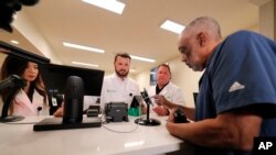 Alex Domino, right, the first ever person to legally receive medical marijuana in Louisiana, purchases his dose at Capitol Wellness Solutions, in Baton Rouge, Louisiana, Aug. 6, 2019.