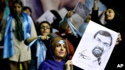 Seorang pendukung kandidat presiden Mohsen Rezaei, mantan komdandan Tentara Revolusi Iran, memegang poster capresnya di saat kampanye di Teheran, Iran (10/6). Pemilu Iran akan diselenggarakan hari Jumat, 14 Juni 2013 mendatang.