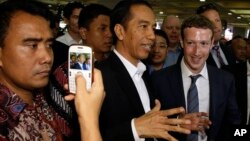 Indonesian President-elect Joko Widodo, center, speaks with Facebook CEO Mark Zuckerberg, right, during their visit to a market in Jakarta, Indonesia, Oct 13, 2014. 