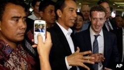 Indonesian President-elect Joko Widodo, center, speaks with Facebook CEO Mark Zuckerberg, right, during their visit to a market in Jakarta, Indonesia, Oct 13, 2014. 