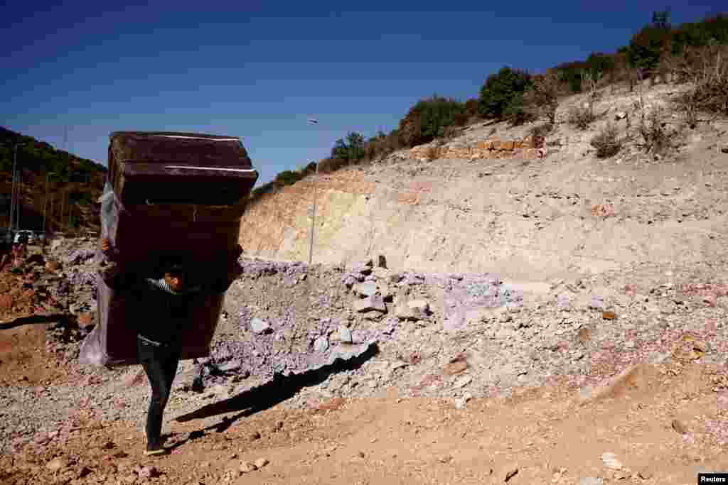 A lad  carries his belongings portion    crossing from Lebanon into Syria connected  ft  astatine  the Masnaa borderline  crossing, aft  an Israeli onslaught   successful  Al Masnaa, Lebanon.