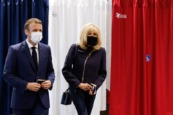 French President Emmanuel Macron (L) and his wife Brigitte Macron leave a polling station after casting their ballots in Le Touquet, in the second round of French regional elections, June 27, 2021.