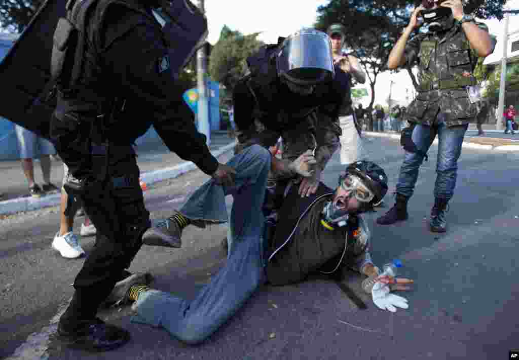 Polisi anti huru-hara menahan seorang pria dalam sebuah demonstrasi anti-pemerintah di Brazil, yang sebagian dipicu oleh miliaran uang yang dikeluarkan untuk mempersiapkan Piala Dunia, di Belo Horizonte (26/6). (AP/Victor R. Caivano)