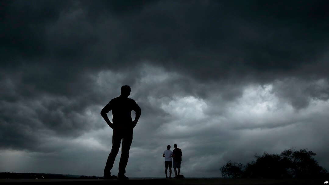 Beberapa orang mengamati cuaca dari Tugu "Liberty Memorial" sementara badai hebat yang memicu serangkaian tornado mendekati pusat kota Kansas, Selasa, 28 Mei 2019. (Foto AP / Charlie Riedel)