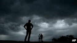 Beberapa orang mengamati cuaca dari Tugu "Liberty Memorial" sementara badai hebat yang memicu serangkaian tornado mendekati pusat kota Kansas, Selasa, 28 Mei 2019. (Foto AP / Charlie Riedel)