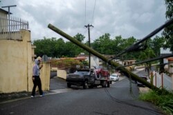 A man guides a tow truck under a downed power line pole after Tropical Storm Isaias hit the area in Mayaguez, Puerto Rico, July 30, 2020.
