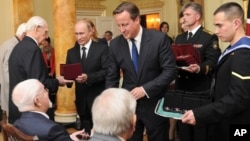 Russian President Vladimir Putin, center left, works with British Prime Minister David Cameron, center right, to award Russian Ushakov medals to Arctic Convoy Veterans, in London, June 16, 2013.