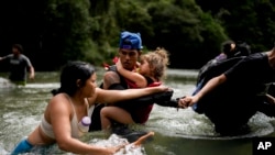 El migrante venezolano Álvaro Calderini lleva a su sobrina a través de un río cerca de Bajo Chiquito, Panamá, después de cruzar el Tapón del Darién desde Colombia en su camino hacia el norte a Estados Unidos, el sábado 9 de noviembre de 2024.