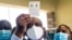 Zimbabwe vice president and Minister of Health Constantino Chiwenga holds up his vaccination certificate after receiving the first shot of Sinopharm, the COVID-19 vaccine from China, Feb. 18 2021.