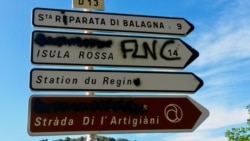 Graffiti supporting Corsica's FLNC liberation movement covers a road sign in the island's Balagne region. (Lisa Bryant/VOA)