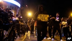 Protesters hold signs and walk past a line of police in downtown Columbus, Ohio, May 28, 2020, during a demonstration over the death of George Floyd in police custody.