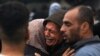 Des Palestiniens pleurent leurs proches, tués lors d'une frappe israélienne nocturne contre le camp de réfugiés d'Al-Maghazi, dans le sud de la bande de Gaza, le 25 décembre 2023.