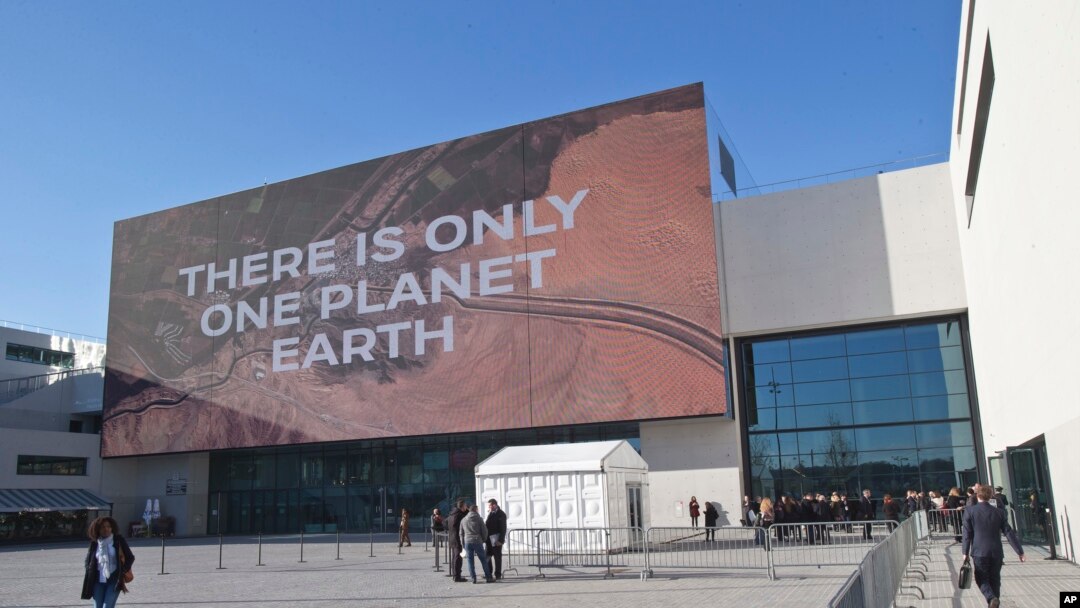 Participants walk past the main entrance of the One Planet Summit, in Boulogne-Billancourt near Paris, France, Dec. 12, 2017. 