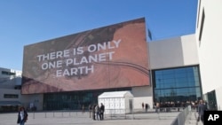 Participants walk past the main entrance of the One Planet Summit, in Boulogne-Billancourt near Paris, France, Dec. 12, 2017. 