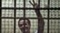 Egyptian political activist Ahmed Douma reacts as he stands behind dock bars during his trial in Cairo on June 3, 2013, on charges of insulting president Mohamed Morsi. 