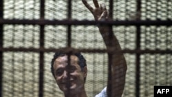 Egyptian political activist Ahmed Douma reacts as he stands behind dock bars during his trial in Cairo on June 3, 2013, on charges of insulting president Mohamed Morsi. 