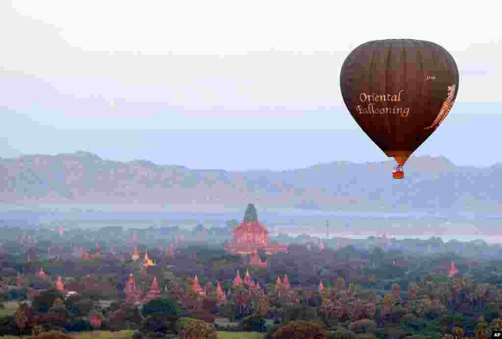 A hot air balloon flies over Myanmar&#39;s ancient temples just before sunrise in old Bagan, Nyaung U district.