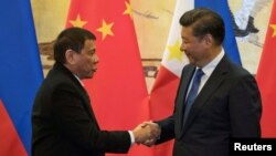 Presiden Filipina Rodrigo Duterte (kiri) dan Presiden China Xi Jinping berjabat tangan dalam pertemuan di Beijing, China, Kamis (20/10).