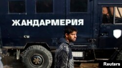 FILE - A man walks in front of a police truck in a Roma neighborhood in the city of Pazadzhik, Bulgaria, Nov. 25, 2014.