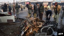 Pakistani security officials examine the site of a suicide bomb attack on the outskirts of Peshawar, Jan. 19, 2016. At least 12 people were killed in a suicide attack on a market during morning rush hour in the outskirts of the northwestern city, official