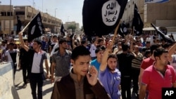 FILE - Demonstrators chant pro-Islamic State group slogans as they carry the group's flags in front of the provincial government headquarters in Mosul, Iraq, June 16, 2014.