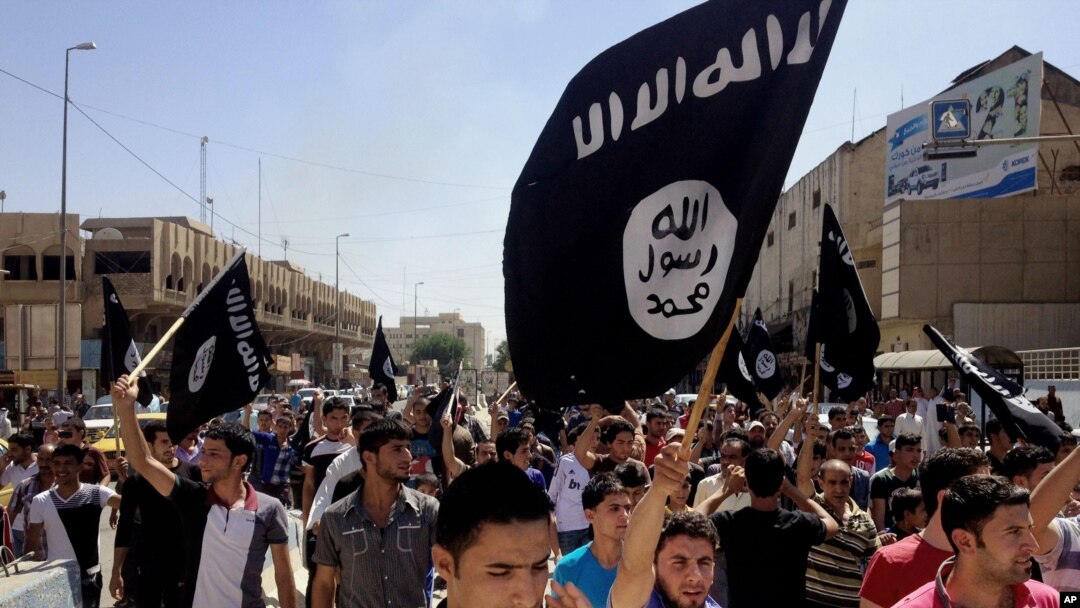 In this June 16, 2014 file photo, demonstrators chant pro-Islamic State group slogans as they carry the group's flags in front of the provincial government headquarters in Mosul, Iraq.