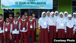 Siswa-siswi SD Al Bina Masohi, Maluku, berfoto dengan spanduk yang menyemangati mereka saat menikuti Ujian Sekolah Berstandar Nasional (UASBN) 2019. (Courtesy: Darno Yusuf Mulyono/SD Al Bina Masohi)