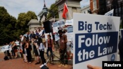A man holds a sign reading “Big Tech Follow the Law” at a demonstration opposing a ballot campaign by big companies to exempt their companies from some labor laws, in Boston, June 22, 2021.