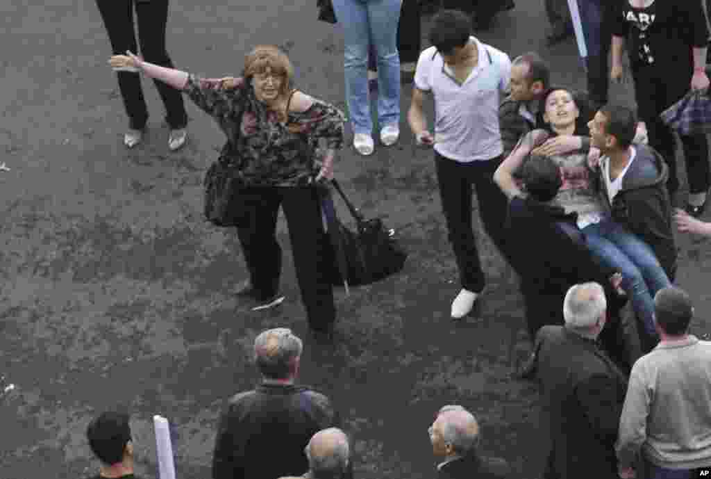People carry a victim (R) of the explosion of gas-filled balloons during a campaign rally in the central Republic Square in Yerevan, May 4, 2012. An explosion injured at least 144 in central Yerevan on Friday during a campaign rally by Armenia's ruling pa