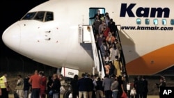 FILE - Afghan evacuees exit a plane after landing at Skopje International Airport, North Macedonia, Aug. 30, 2021. North Macedonia hosted the first group of about 150 Afghan evacuees who made it out of their country after days of chaos, following the takeover by the Taliban.